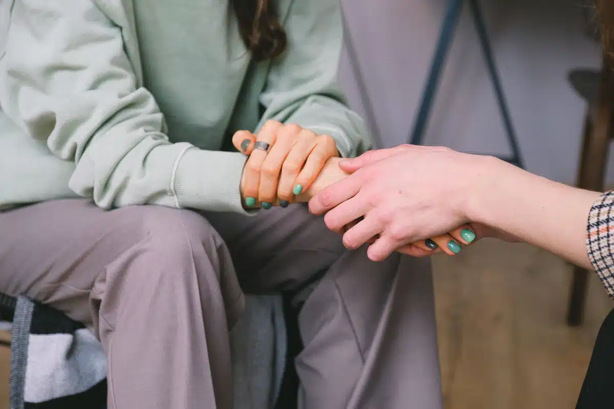 Close-up of supportive handholding during a mental health counseling session for cobb outpatient detox.